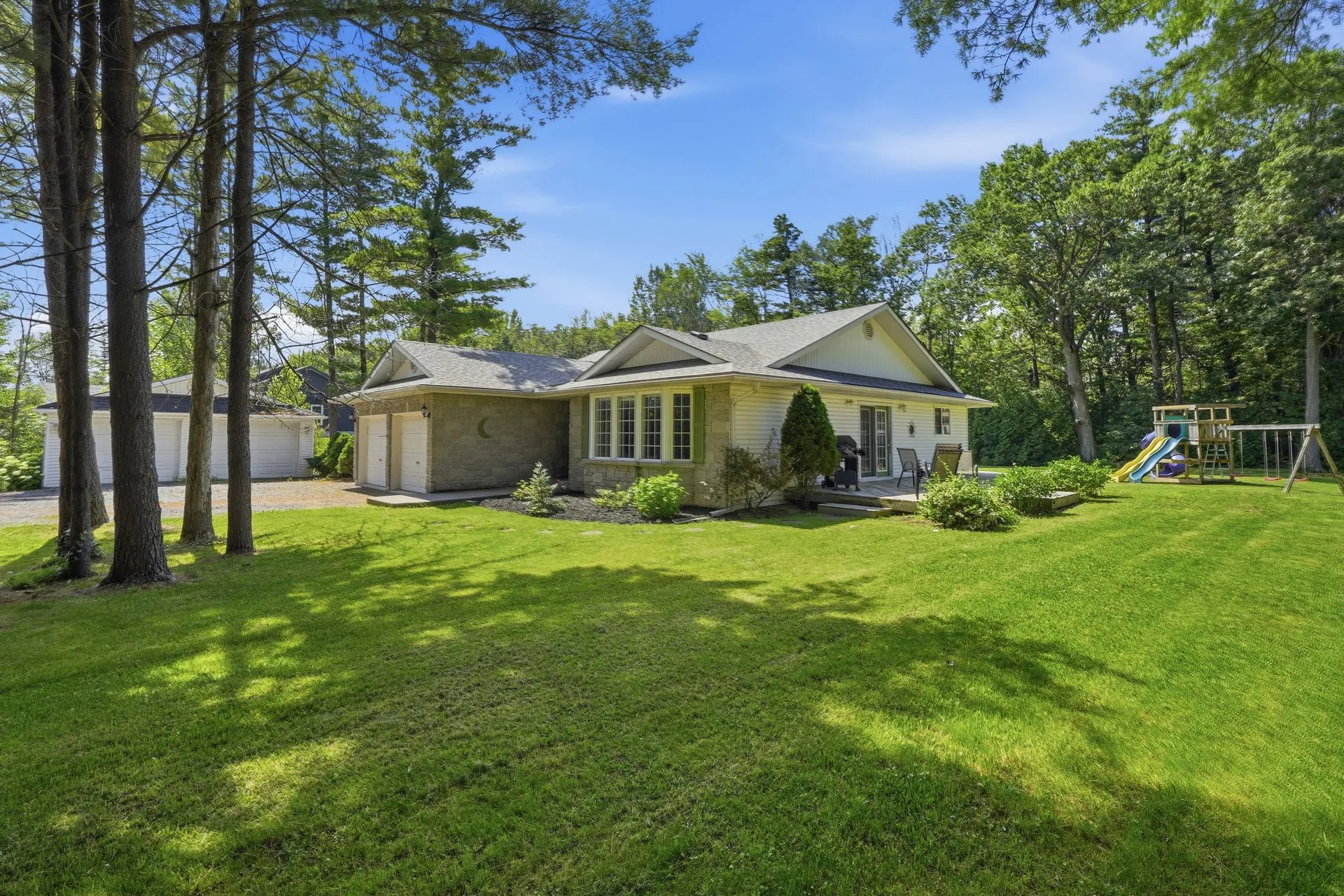 Wide front view of 21627 Loyalist Parkway bungalow and lawn with mature trees, Carrying Place, PEC