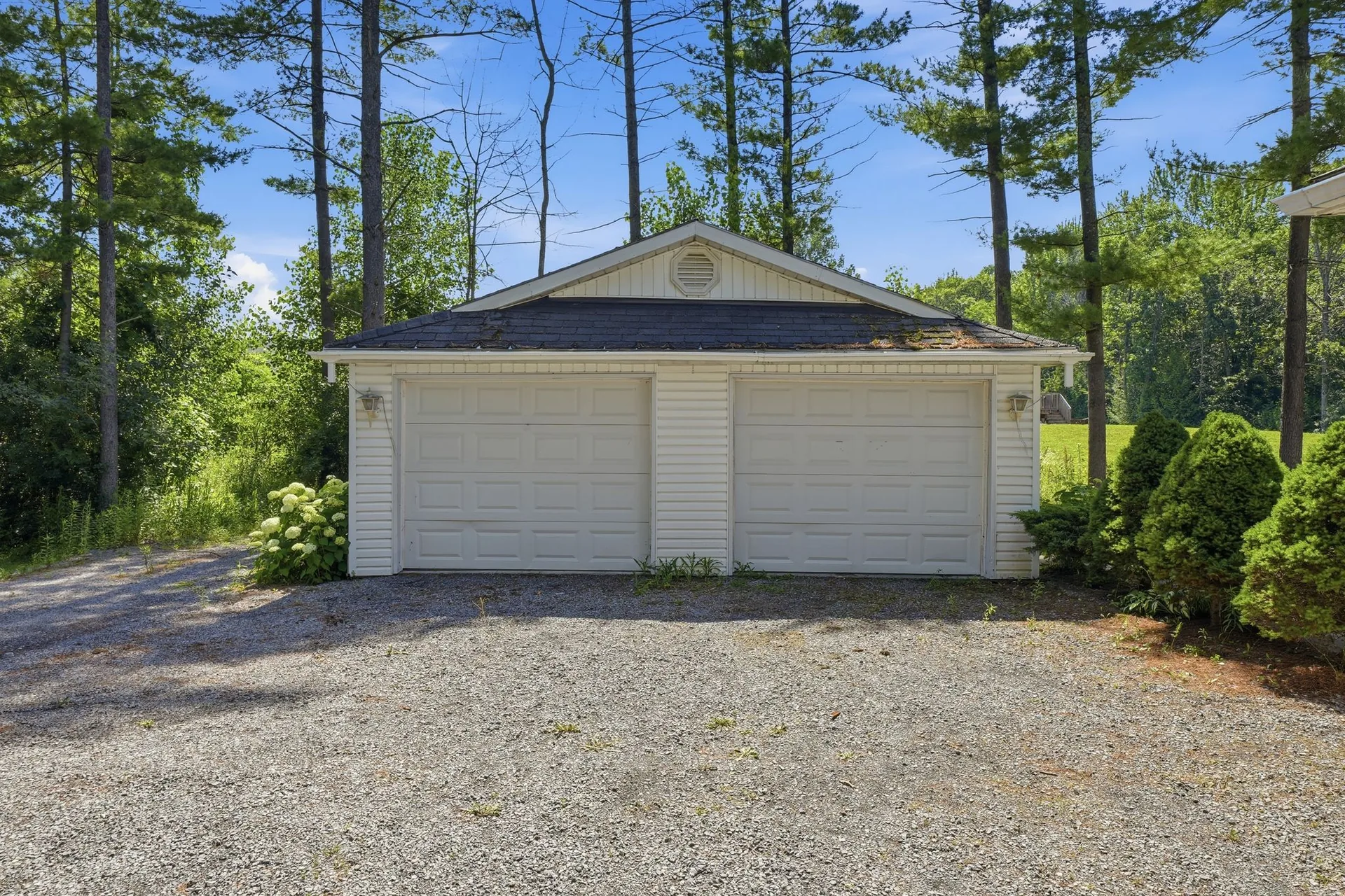 Detached two-car garage and workshop framed by mature pines at 21627 Loyalist Parkway, Carrying Place, Prince Edward County