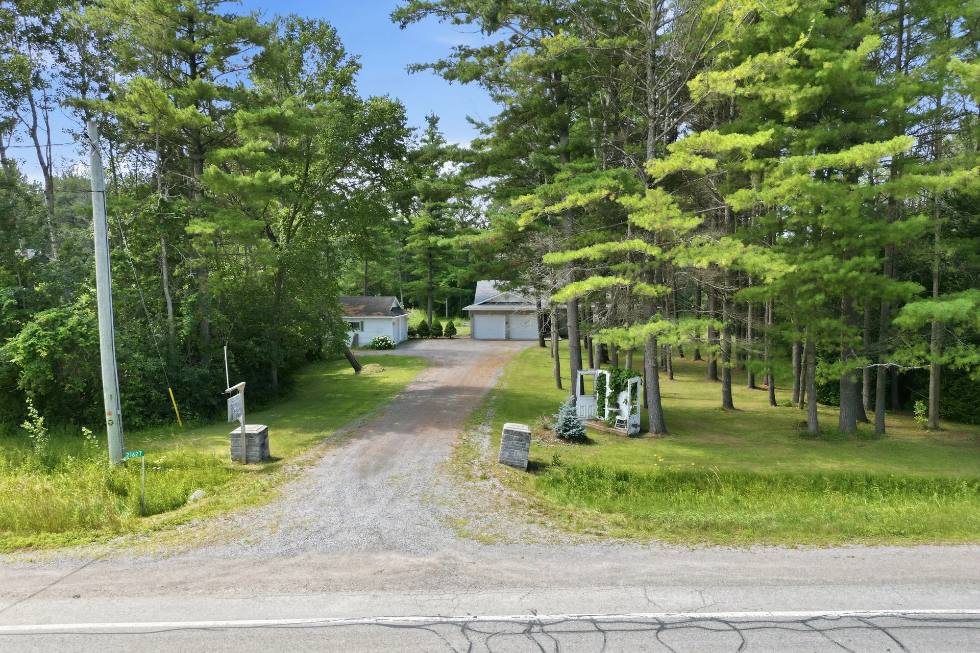 Long private gravel driveway through mature trees leading to 21627 Loyalist Parkway, Carrying Place, PEC