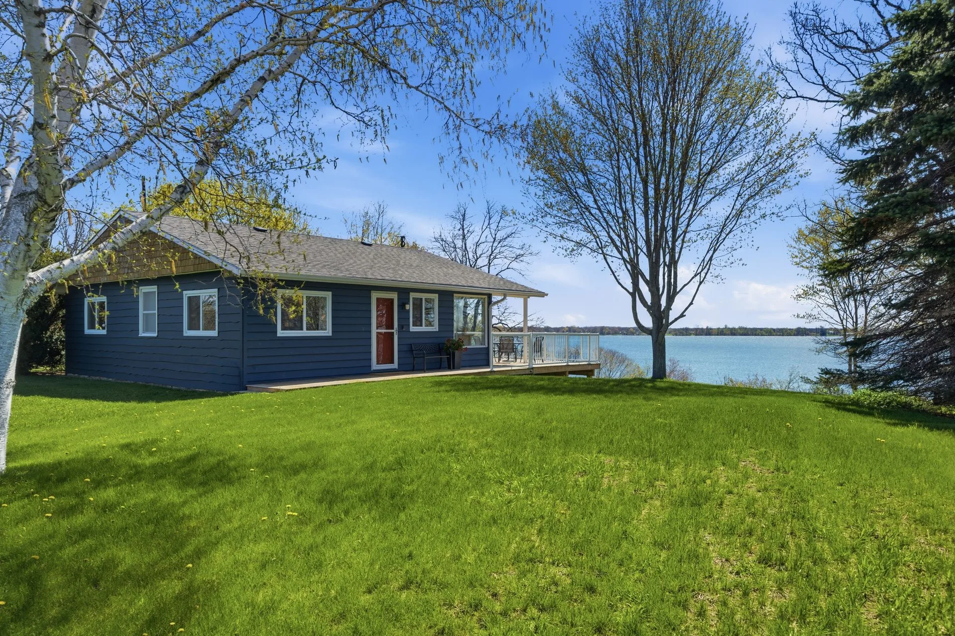 Exterior of 86 Colliers Road waterfront cottage with South Bay in the background, Prince Edward County