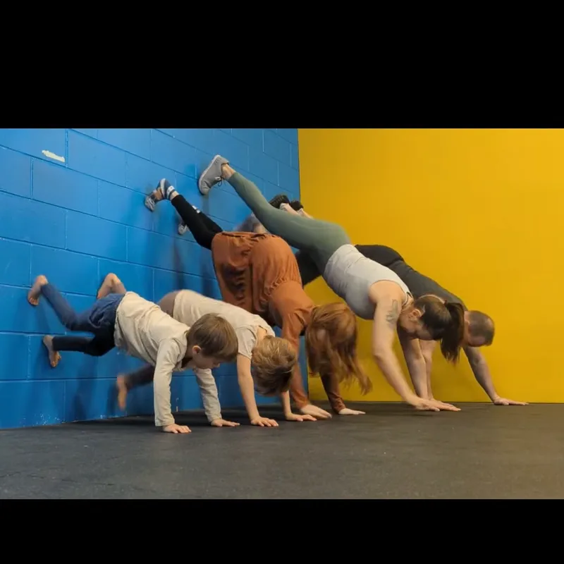 The Bergeron family doing wall handstands together at the gym