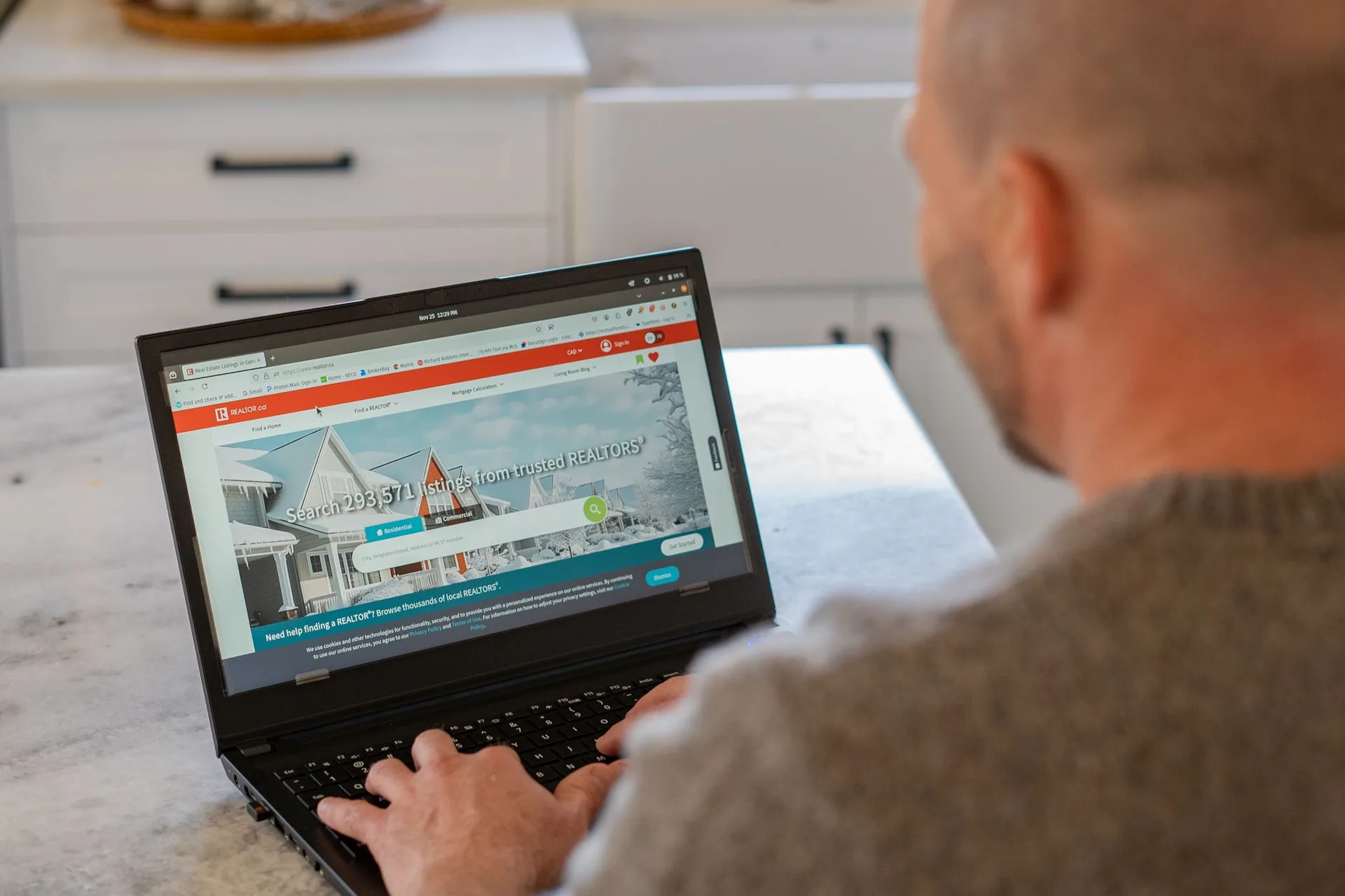 Jake Bergeron searching REALTOR.ca listings on a laptop
